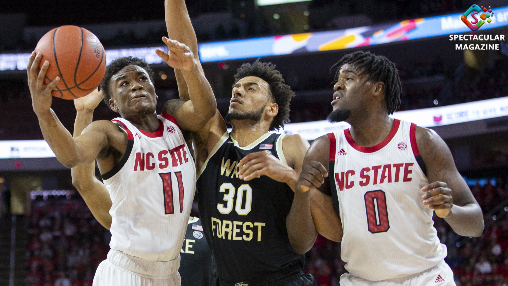 NC State senior guard Markell Johnson (left) attempts a layup against Wake Forest's Olivier Sarr (middle) on senior night at PNC Arena in Raleigh, N.C., Friday, Mar. 6, 2020. NCSU defeated WFU 84-64.