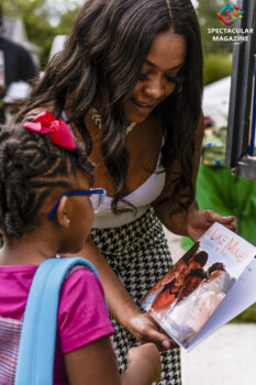 Wall Street Juniors founder MaKayla Booker displays a book from the WSJ Reader's Bank to a child in Old North Durham, N.C., Saturday, Aug.1.