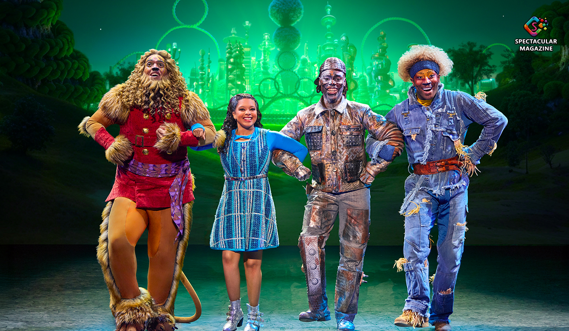 Cast of The Wiz on stage in colorful costumes with Emerald City in the background