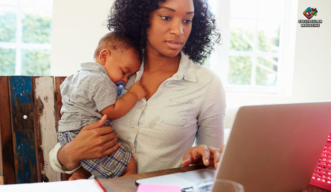 A working mother demonstrates balance as she holds her baby while focusing on her laptop at home.