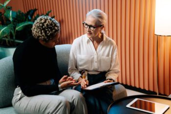 Two women having a focused conversation in a modern office, discussing strategies for achieving work-life balance.