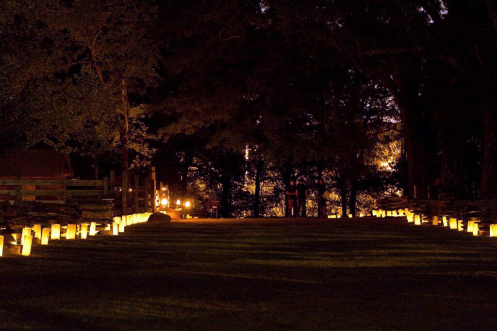 Rows of glowing luminaries light up a grassy path at Bennett Place State Historic Site in Durham during a nighttime event commemorating enslaved people’s journeys to freedom in North Carolina.