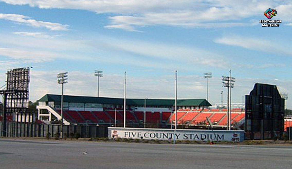 Exterior view of Five County Stadium in Zebulon, North Carolina, showing the grandstands, light towers, and stadium signage near the entrance.