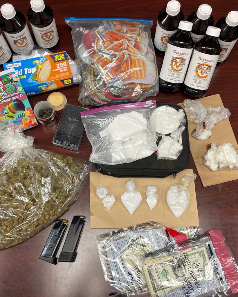 Bags of cocaine, marijuana, cash, and codeine bottles displayed on a table after a Nash County Sheriff’s Office drug bust at Rocky Mount group home.