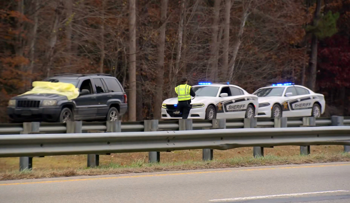 Vehicle stopped on US-64 with a Wake County Sheriff’s patrol car positioned behind it, emergency lights flashing during an active shooting investigation