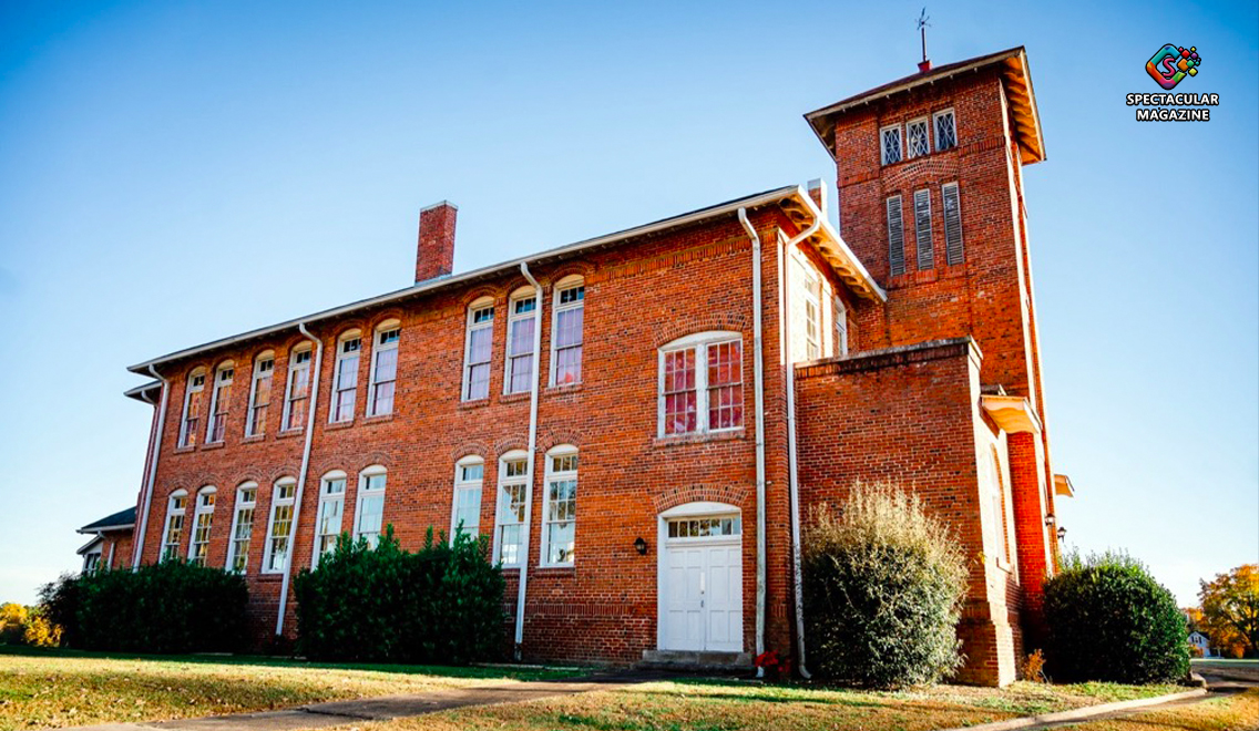 Historic red-brick main building of the Central Children’s Home of North Carolina in Oxford, featuring tall arched windows, a square tower, and a clear blue sky.